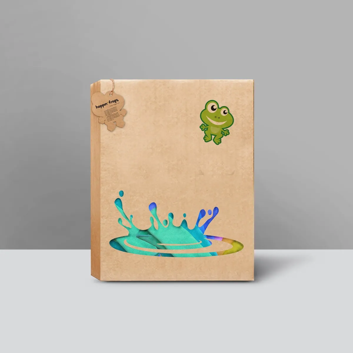 hoppin' frogs kraft gift box (jump variant) — small leaping frog mascot top-right, large die-cut water-splash window at base; natural kraft board, frog hang tag