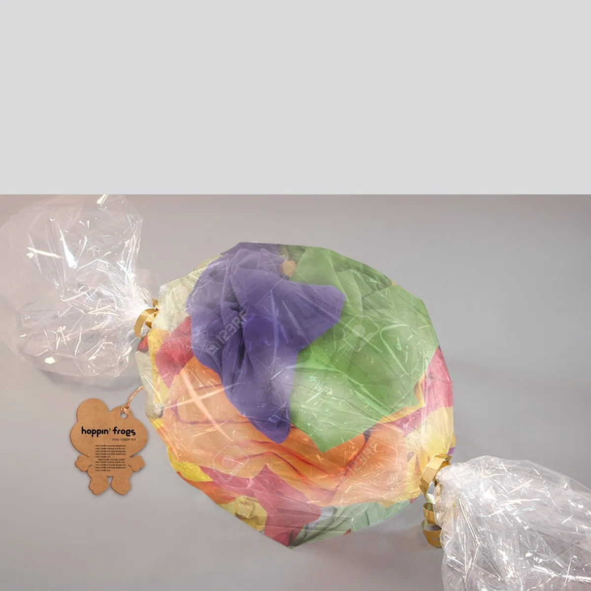 hoppin' frogs candy-wrap packaging — colourful children's underwear bundled into a giant sweet shape with clear cellophane and gold ties at each end; frog hang tag attached