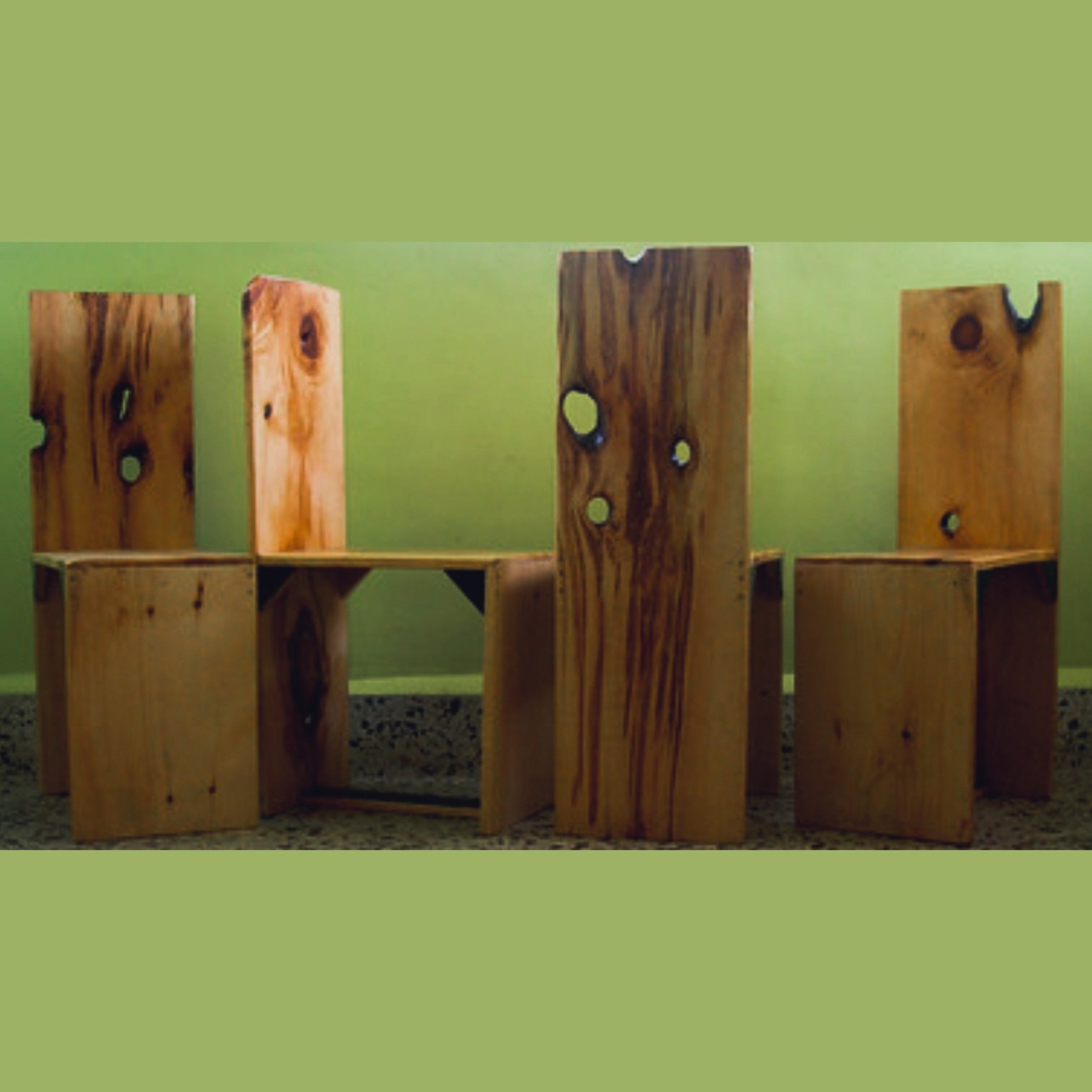 Four chunky pinewood dining chairs with tall slatted backs and natural knot-holes, photographed against a green wall — the "(s)crappy dining chairs"