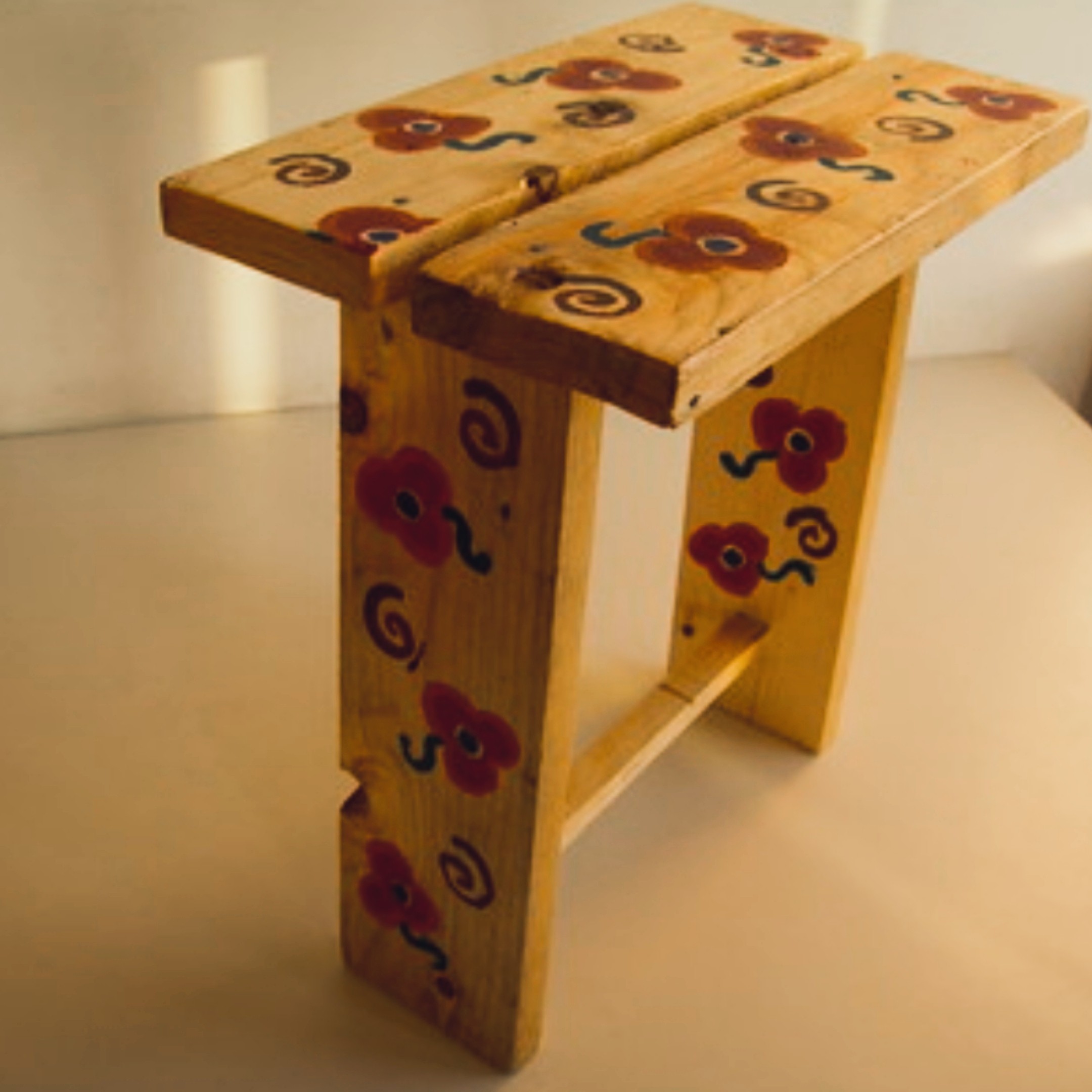The same side table now covered in hand-painted red flowers and blue spirals on every surface