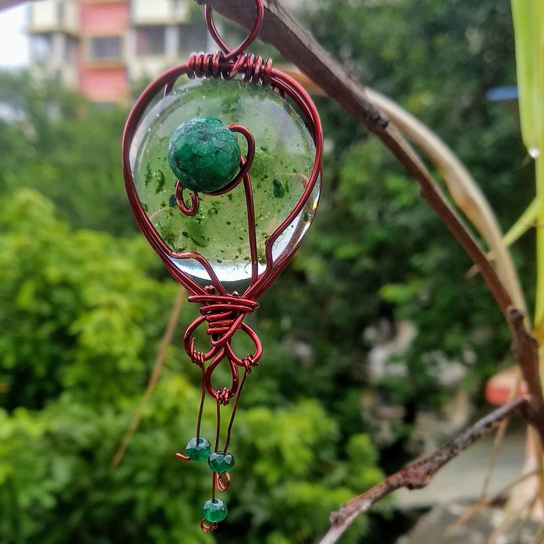 Elaborate copper wire heart pendant — clear round resin dome encasing a green moss ball and plant material, dangling green crystal beads below