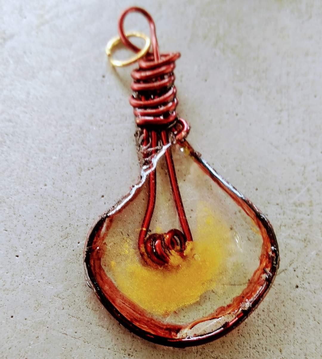 Teardrop resin pendant with copper wire wrapping at the top — amber yellow resin interior with wire detail inside